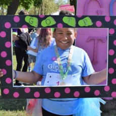 A Girls on the Run participant smiles in the photo opp section of the 5K event.